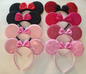 A Quinceanera themed image featuring a petal hair accessory and three Minnie Mouse ears with bows on them.
