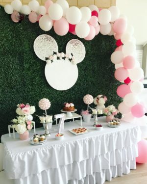 Quinceañera celebration with a table decorated with a white tablecloth and pink and white balloons