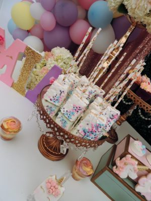 A Quinceanera baking party, featuring a table topped with lots of cupcakes and desserts