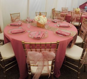 A Quinceanera party with a table set with pink tablecloths and pink napkins.