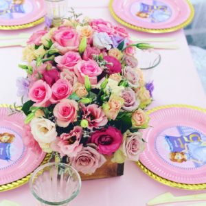 A Quinceanera table with pink plates and a beautiful floral bouquet