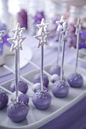 A Quinceanera party with Sofia the First decorations. The image shows a tray of purple and silver Quinceanera cake pops.