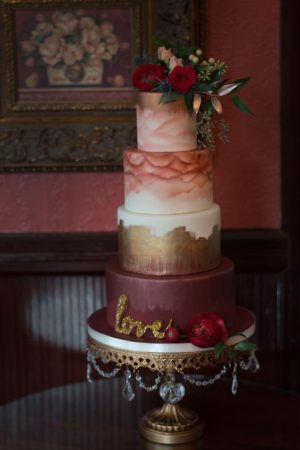 A beautiful burgundy Quinceanera cake. The three-tiered cake is elegantly decorated with flowers on top.
