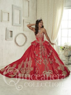 A woman posing for a picture in a gold and red Quinceañera dress.