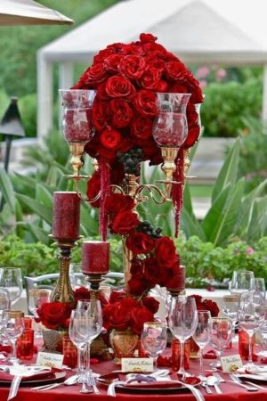 A stunning Quinceanera table set with red roses and candles, featuring red Quinceanera centerpieces