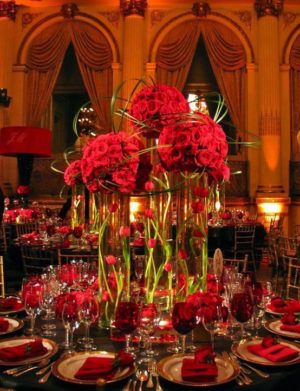 A Quinceanera-themed table set with a red flower arrangement and candles.
