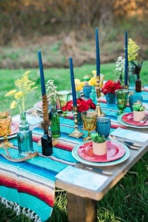 A southwestern inspired Quinceanera table set with a colorful table cloth and place settings