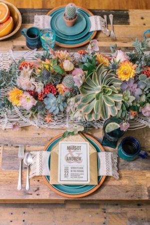 A Quinceanera boho tablescape featuring a wooden table topped with plates and flowers