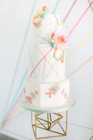 A Quinceanera cake with geometric patterns and purple flowers on top