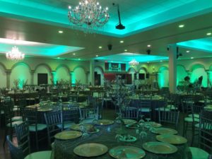 A Quinceanera function hall restaurant with tables and chairs, and a chandelier.
