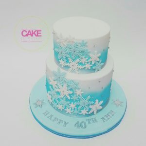 A Quinceanera cake with blue and white decorations, including snowflakes.