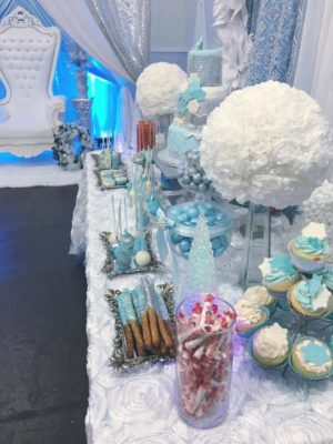 A Quinceanera centrepiece party with a table topped with lots of cupcakes and desserts.