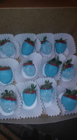 A tray of blue chocolate covered strawberries and a buttercream cupcake for a Quinceanera celebration.