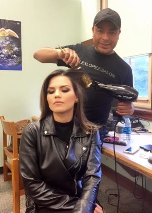 A Quinceanera girl getting her hair blow dried by a hairdresser while sitting in a chair.