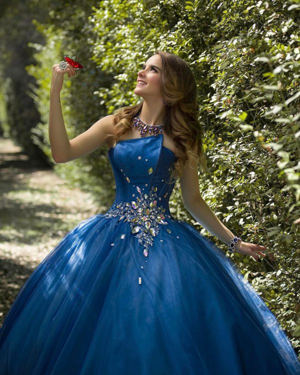 A woman in a blue ball gown posing for a picture wearing a beautiful Quinceañera dress
