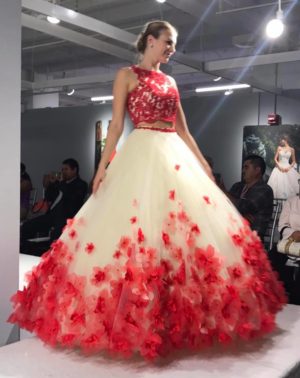 A woman is walking down a runway wearing a red and white dress, gown 89175 Vizcaya by Morilee