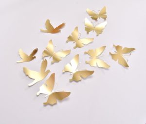 A Quinceanera image showing a golden butterfly wall decor Wall Decal. There is a white table topped with lots of gold butterflies.