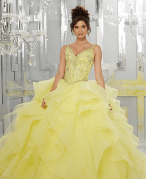 A woman in a yellow Quinceañera gown posing for a picture