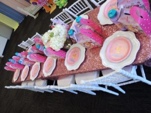A Quinceanera dessert party with a table topped with lots of pink and white plates