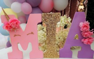 Quinceañera centrepiece: A table topped with pink and purple letters and balloons