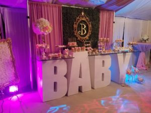 A Quinceañera celebration is taking place in a function hall, with a baby shower set up in a tent