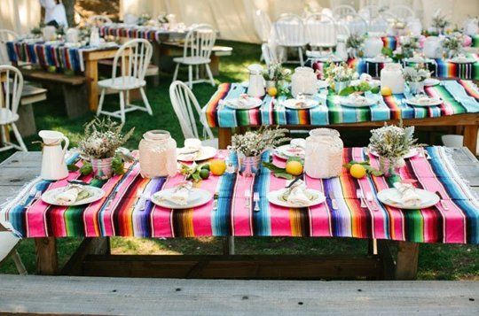 A vibrant Quinceañera table set up with colorful tablecloths and plates