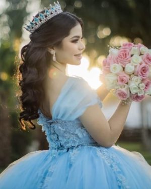 Quinceanera with quince hairstyles wearing crown and a woman in a blue dress holding a bouquet