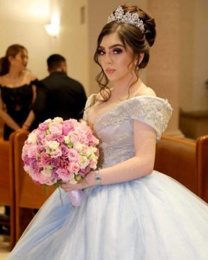 A woman in a Quinceanera gown and hairstyle, holding a bouquet