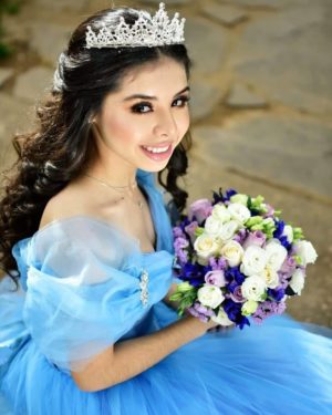 Quinceanera: a woman in a blue dress holding a bouquet, wearing a bride Tiara