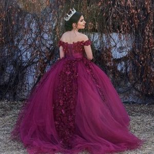 A woman in a purple gown Quinceañera, standing in front of a tree