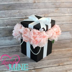 A quinceanera floral bouquet in a black and white box with pink flowers