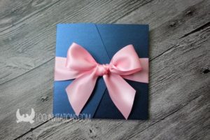 A blue card with a pink bow on it among ribbon Quinceañera dresses
