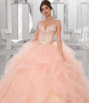 A woman in a ball gown posing for a picture at a rose gold themed Quinceañera, wearing Quinceañera dresses.