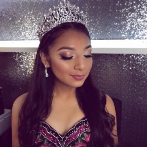 A beautiful woman with long hair wearing a tiara and a Quinceanera dress