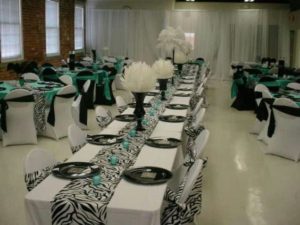 A Quinceanera celebration with a zebra print theme. The room is filled with lots of tables covered in black and white linens.