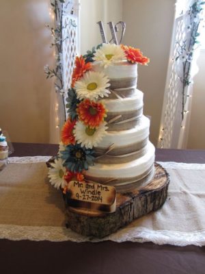 A Quinceanera cake with brown twine and flowers on a table