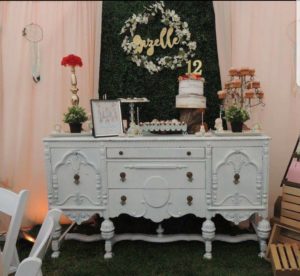 A Quinceanera-themed chest of drawers table with a cake on top
