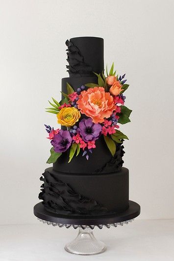 A Quinceanera cake with a gothic style, a black cake with flowers on top of it