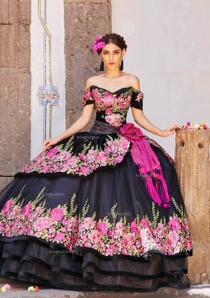 A woman in a black and pink dress posing for a picture in a charro quince dress at a Quinceanera event.