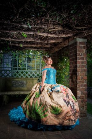 A woman in a Quinceanera dress sitting on a bench at Planting Fields Arboretum State Historic Park.