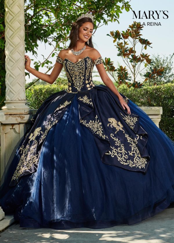 A woman in a navy blue charro Quinceanera dress standing elegantly in a blue and gold ball gown