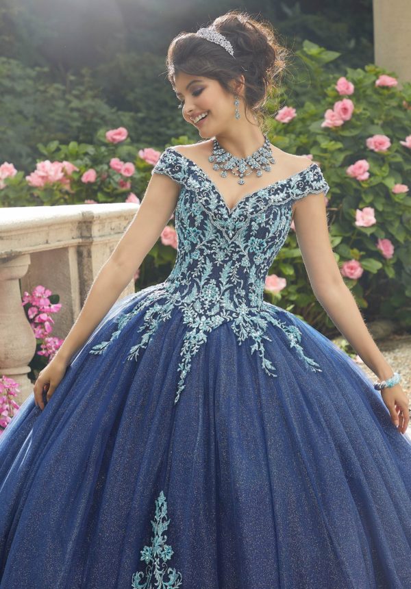 A woman in a dark navy blue Quinceañera dress posing for a picture.