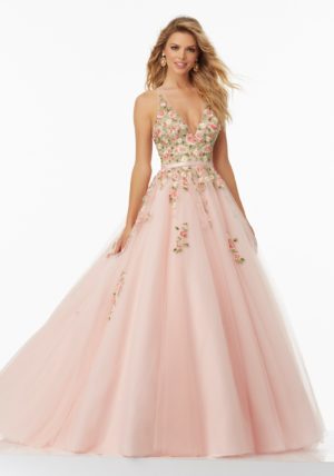 A woman in a pink ball gown, wearing a floral embroidered tulle prom dress for a Quinceanera