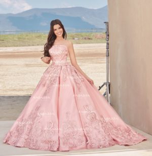 A woman in a pink dress posing for a picture in gown Quinceañera dresses