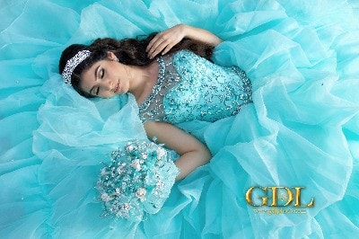 Beauty Quinceañera, a woman in a blue dress laying on a bed