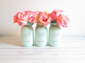Three Quinceanera-themed mason jars with flowers on a table