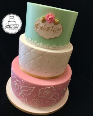 A Quinceanera cake decorated with pink and green frosting in three tiers