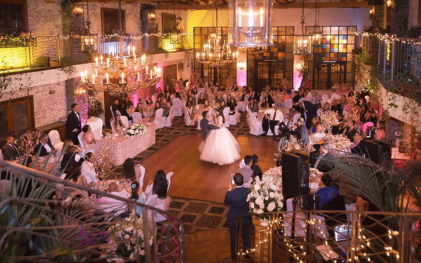 A group of people standing around a Quinceanera reception at Michael's Tuscany Room, with Quinceañera dresses on display
