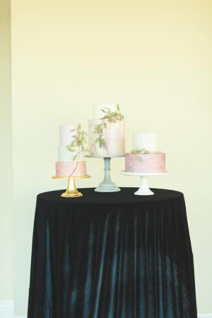 A Quinceanera themed table with three cakes on top of it.