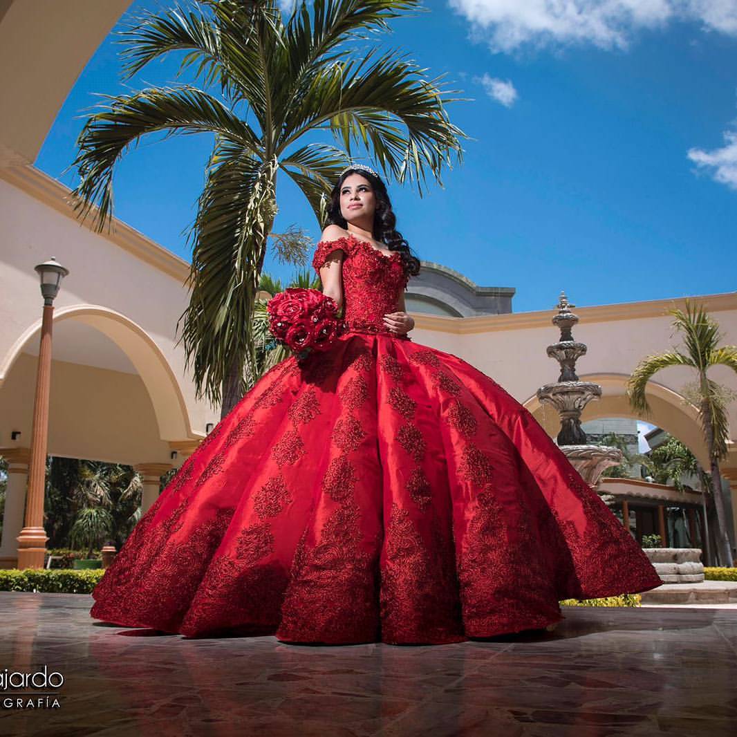 A woman in a red dress posing for a picture wearing quinceanera dramatic dresses